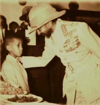a man in a military uniform shaking hands with a young boy